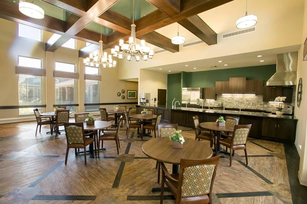 Bright common area with tables and chairs in a senior living facility.