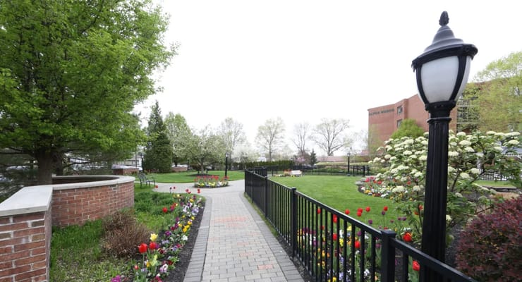 A paved path surrounded by colorful flowers and greenery at The Philadelphia Protestant Home.