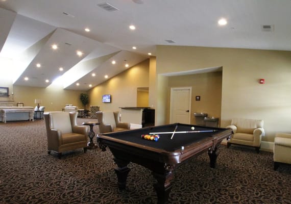 A billiards table in a spacious lounge area with seating.