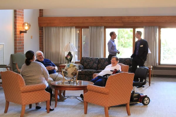 Seniors chatting in the lounge area with a globe and lamp