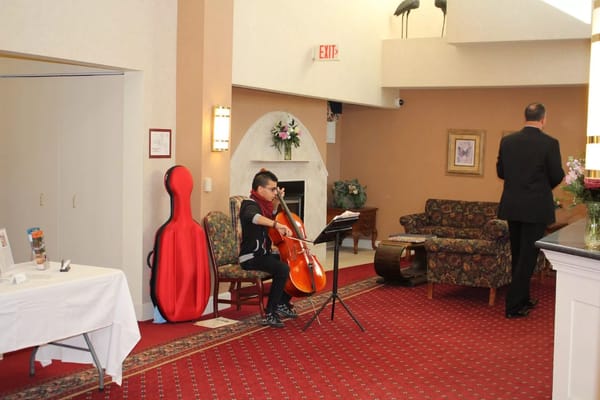 A musician playing the cello in a common area.