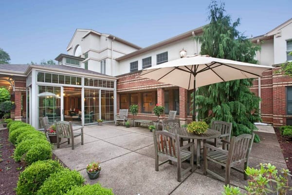 A patio with wooden furniture and an umbrella at The Pines of Mount Lebanon.