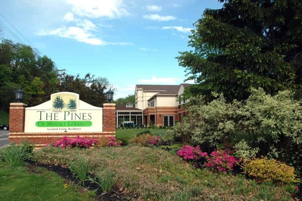 Sign of The Pines of Mount Lebanon assisted living residence surrounded by flowers