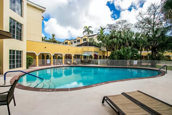 Outdoor pool area with lounge chairs and palm trees