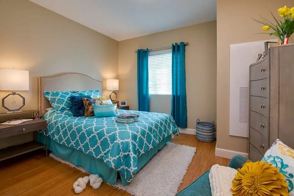 Brightly colored bedroom with teal bedding and natural light.