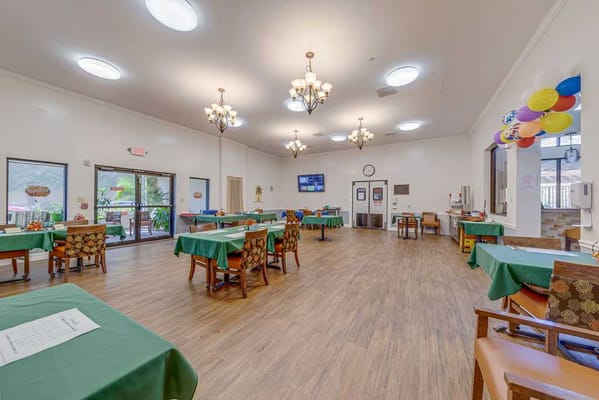 Empty dining room with tables set for dining, featuring green tablecloths.