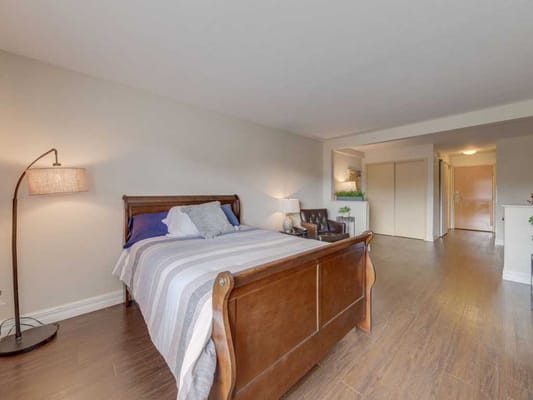 A cozy bedroom with a wooden bed, lamp, and seating area