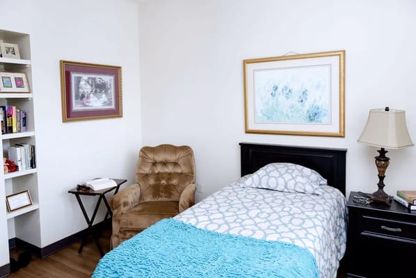 A well-decorated bedroom featuring a bed, bedside table, lamp, and armchair.