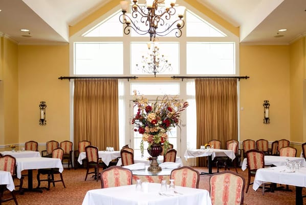 Elegant dining area with tables, floral centerpiece, and chandelier