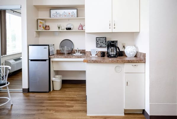 Compact kitchenette with a refrigerator and coffee maker.