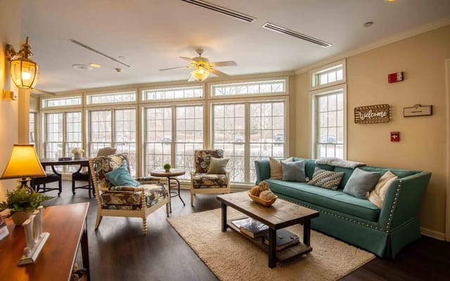 A comfortable living room with seating and large windows at The Residence at Presque Isle Bay.