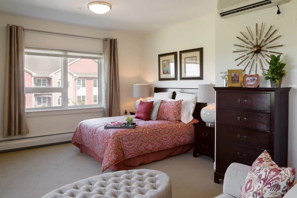 A cozy bedroom with a colorful bedspread and large window.