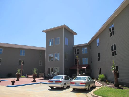 Courtyard area of The Residences at Bay Cove with palm trees and vehicles