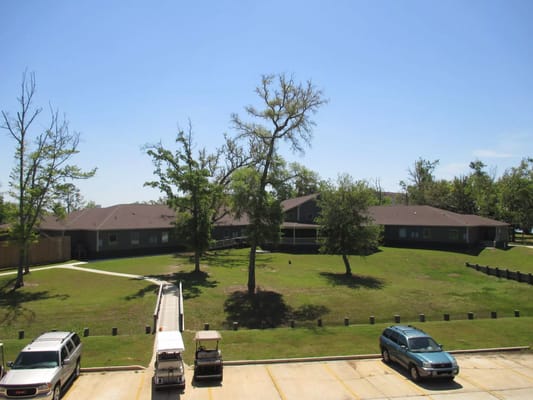 View of The Residences at Bay Cove with landscaped grounds and parked cars.