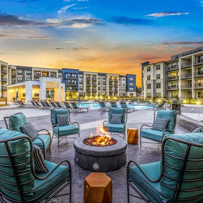 Cozy fire pit with seating around a swimming pool at sunset.