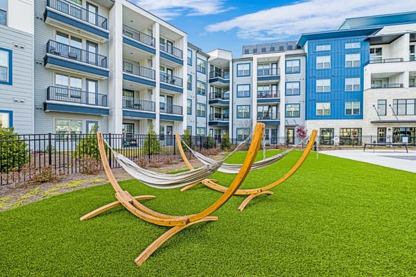 Wooden hammocks on green grass near apartment buildings