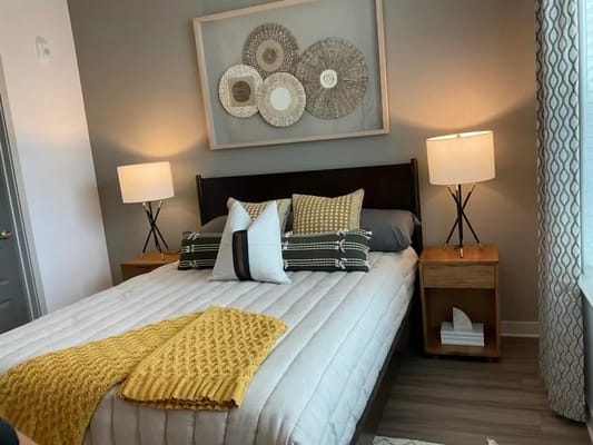 Well-decorated bedroom with a bed, lamps, and colorful throw blankets