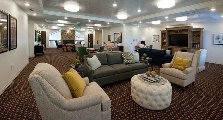 Spacious common area in a senior living facility featuring comfortable seating and warm lighting.