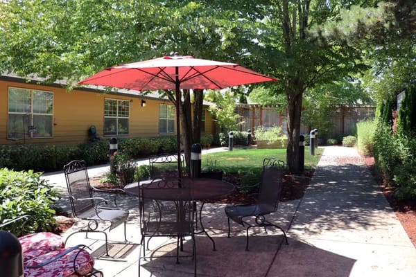 Outdoor seating area with red umbrella in a garden