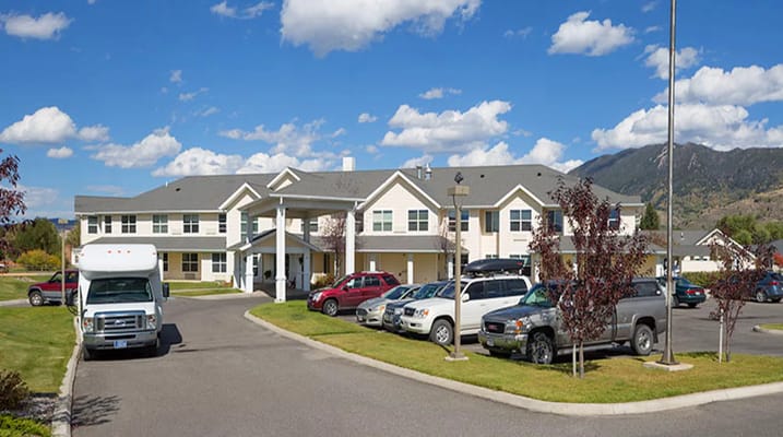 Exterior view of assisted living facility with vehicles in parking lot