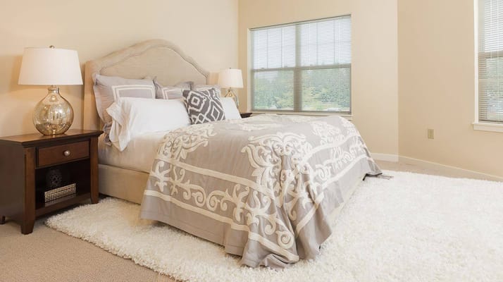 A well-decorated bedroom with a plush bed and bedside lamp.