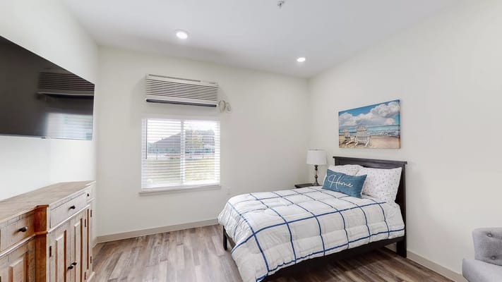 A well-decorated bedroom with a bed, TV, and window