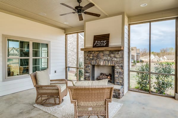 Screened porch with wicker chairs and a stone fireplace