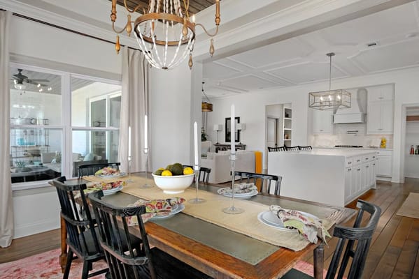 A cozy dining room featuring a wooden table set with dishes and a fruit bowl.