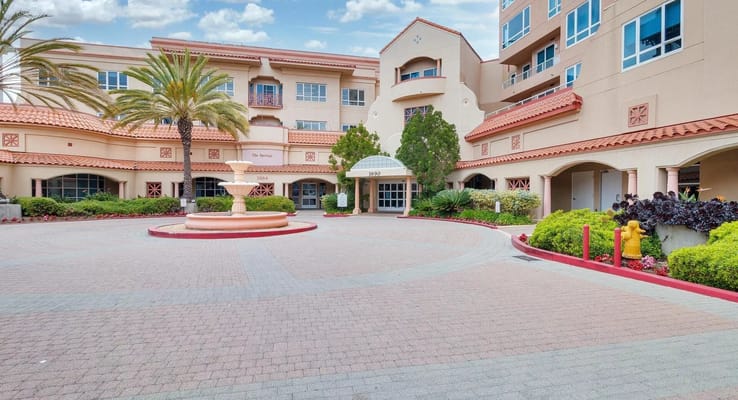 The entrance area of The Springs of Pacific Regent featuring a fountain and landscaped gardens.