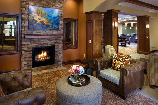 Cozy living room with fireplace and armchairs at The Terraces of Boise.