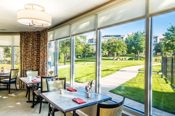 Bright dining area with tables set for meals and views of the garden outside