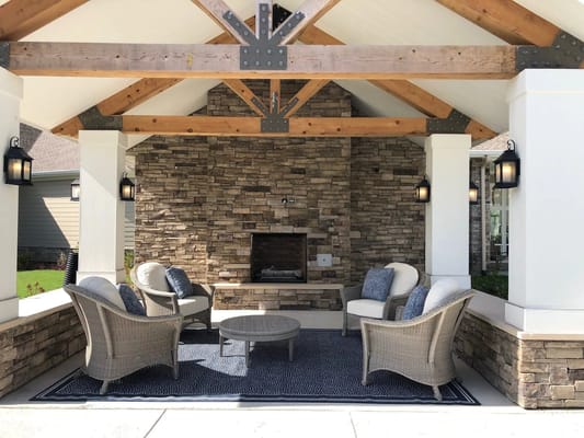 Cozy outdoor lounge with seating and a stone fireplace