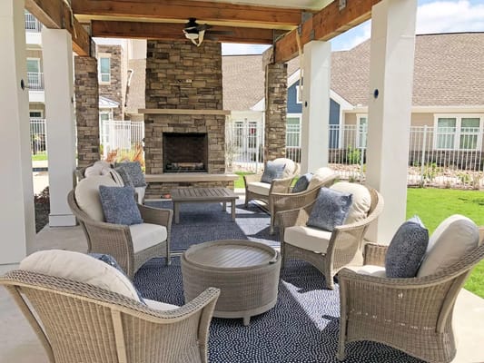 Cozy outdoor lounge area with seating and a stone fireplace.