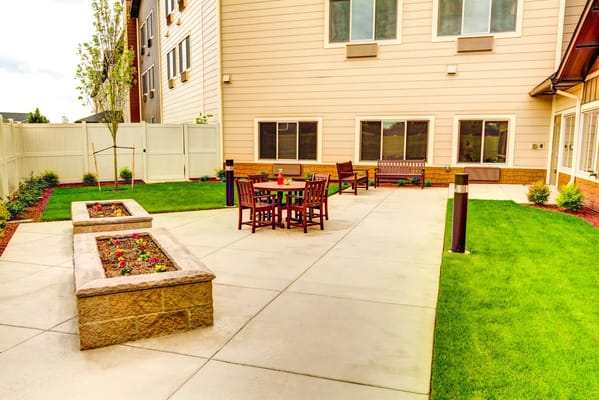 Outdoor seating area with tables and flower beds at The Village at Keizer Ridge.