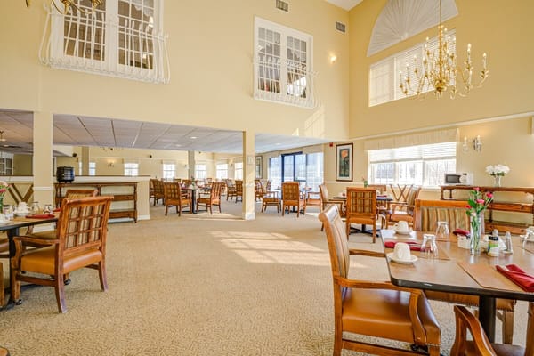 Spacious dining area in a senior living facility with tables and chairs.
