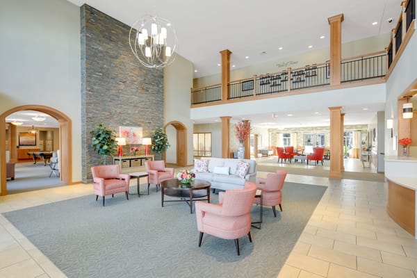 Modern lobby seating area with light pink chairs and stone feature wall