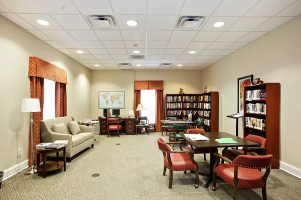 Cozy common area with bookshelves, seating, and workstations.