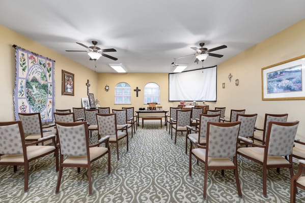 A spacious activity room with empty chairs and wall decorations.