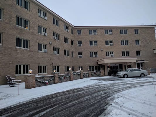 Snow-covered entrance and exterior of The Woods of Caledonia senior living facility