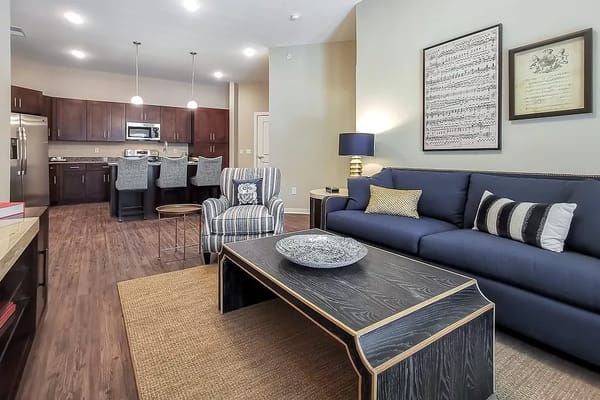 Spacious living room with a blue sofa and kitchenette