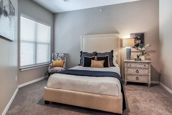 A well-furnished bedroom with a bed, side table, and armchair.