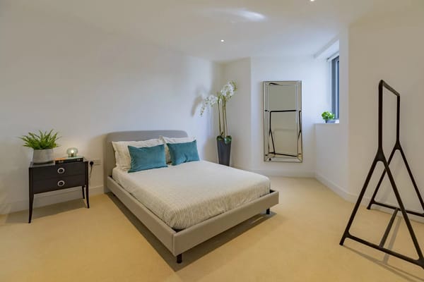 Bright and modern bedroom with a bed, nightstand, and mirror