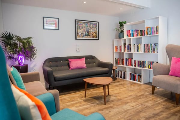 Cozy lounge area with a sofa, bookshelves, and decorative plants.