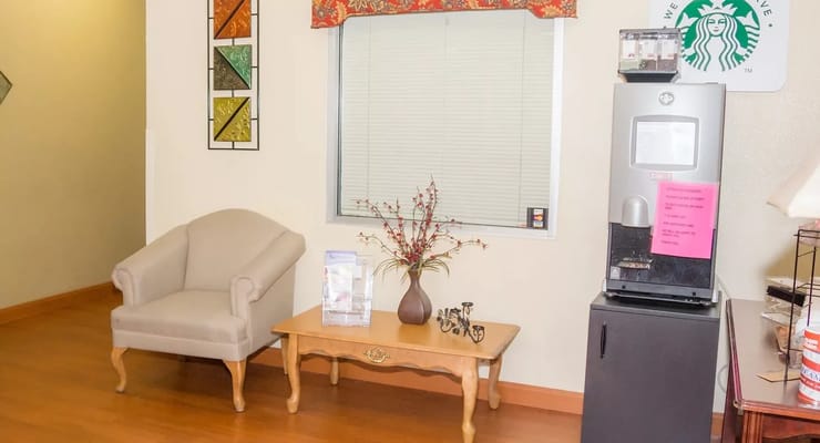 Cozy lounge area with a chair, coffee station, and decorative table.