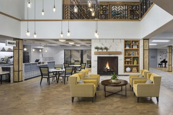 Cozy living area with yellow chairs, a fireplace, and dining tables