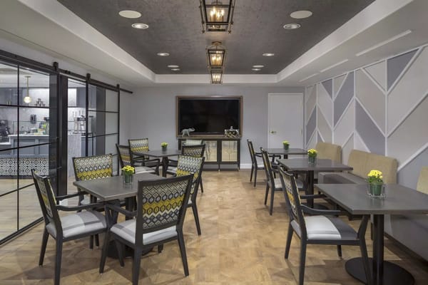 Modern dining room with tables and chairs set up for residents