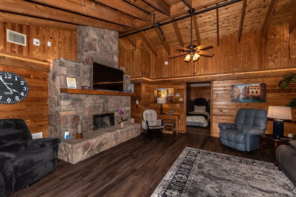A warm living room with stone fireplace and wooden walls at Town and Country Assisted Living.