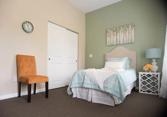 Brightly decorated resident room with bed and chair