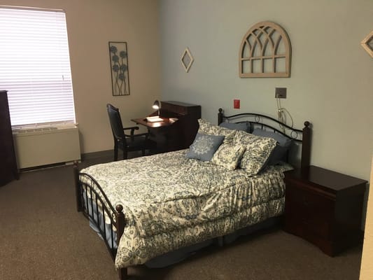 A comfortable bedroom featuring a bed, desk, and decorative elements