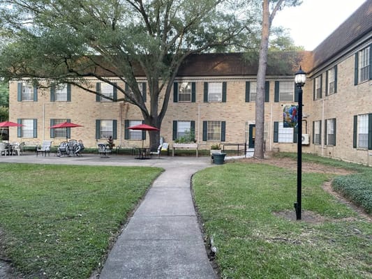 Seating area with red umbrellas and a pathway at Treemont Health Care Center.